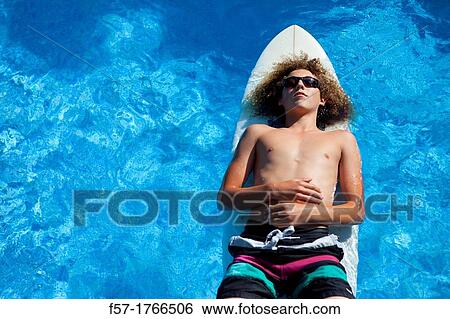 Teenage boy chilling on his surfboard View Large Photo Image Stock Photograph - Teenage boy chilling on his surfboard. Fotosearch