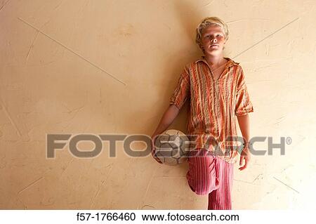 Stock Image - Teenage boy holding a football. Fotosearch