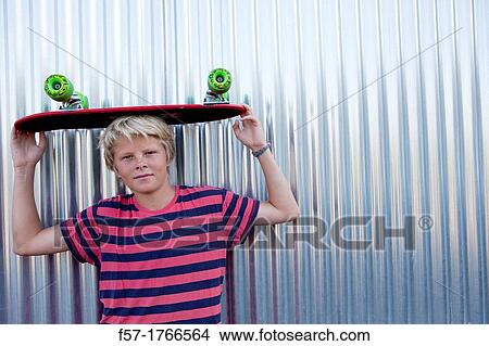 Teenage boy holding a longboard on his head View Large Photo Image Picture - Teenage boy holding a longboard on his head. Fotosearch