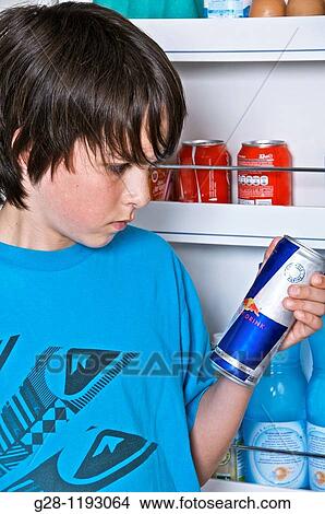 Teenage boy,, in blue, in the kitchen, in front of a fridge, holding a can of energy drink View Large Photo Image Picture - Teenage boy,, in blue, in the kitchen, in front of a fridge, holding a can of energy drink. Fotosearch
