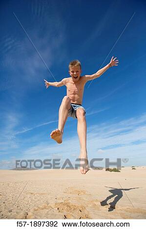 Teenage boy jumping in the air over the dunes View Large Photo Image Stock Image - Teenage boy jumping in the air over the dunes. Fotosearch