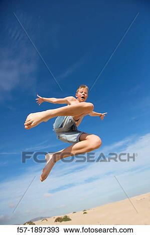 Teenage boy jumping in the air over the dunes View Large Photo Image Stock Image - Teenage boy jumping in the air over the dunes. Fotosearch