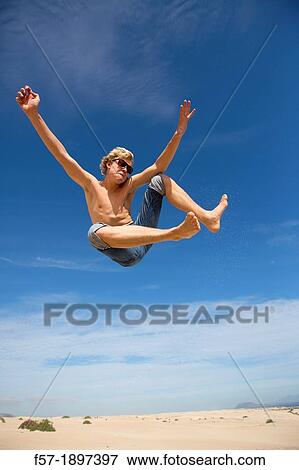 Teenage boy jumping in the air over the dunes View Large Photo Image Stock Photo - Teenage boy jumping in the air over the dunes. Fotosearch