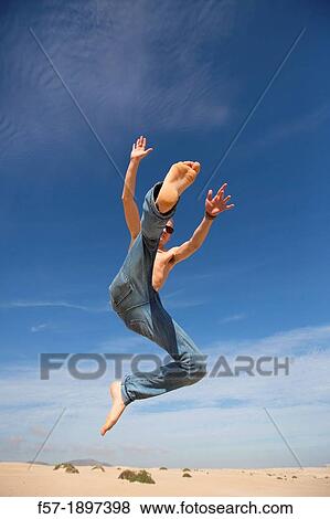 Teenage boy jumping in the air over the dunes View Large Photo Image Stock Photo - Teenage boy jumping in the air over the dunes. Fotosearch