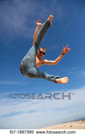 Teenage boy jumping in the air over the dunes View Large Photo Image Stock Photo - Teenage boy jumping in the air over the dunes. Fotosearch