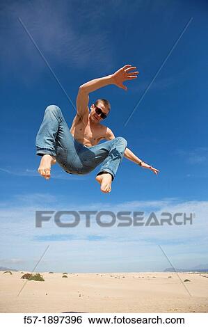 Teenage boy jumping in the air over the dunes View Large Photo Image Stock Photograph - Teenage boy jumping in the air over the dunes. Fotosearch