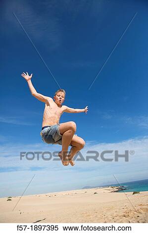 Teenage boy jumping in the air over the dunes View Large Photo Image Stock Photography - Teenage boy jumping in the air over the dunes. Fotosearch