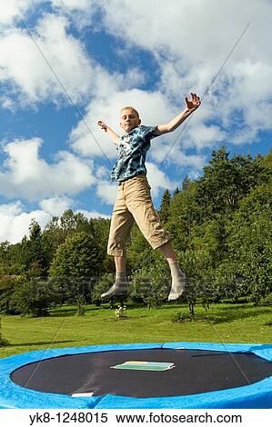 Stock Photography - Teenage Boy Jumping on Trampoline. Fotosearch