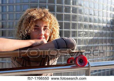 Stock Image - Teenage boy leaning on his skateboard. Fotosearch