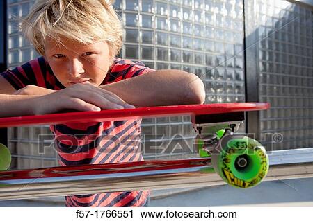 Teenage boy leaning on his skateboard View Large Photo Image Stock Image - Teenage boy leaning on his skateboard. Fotosearch