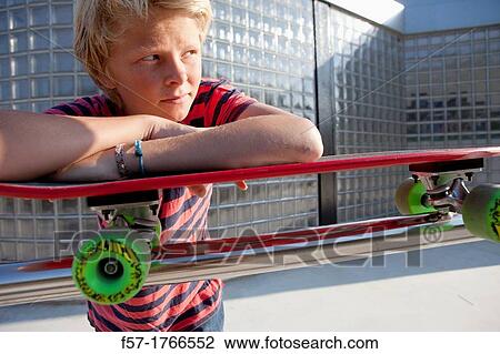 Teenage boy leaning on his skateboard View Large Photo Image Stock Image - Teenage boy leaning on his skateboard. Fotosearch