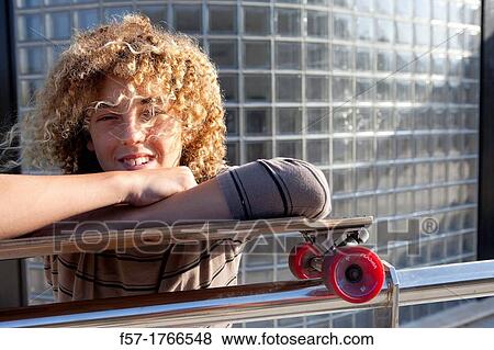 Teenage boy leaning on his skateboard View Large Photo Image Stock Photo - Teenage boy leaning on his skateboard. Fotosearch