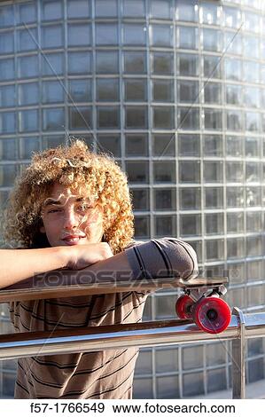 Stock Photo - Teenage boy leaning on his skateboard. Fotosearch