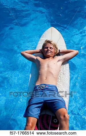 Teenage boy lying on his surfboard View Large Photo Image Picture - Teenage boy lying on his surfboard. Fotosearch