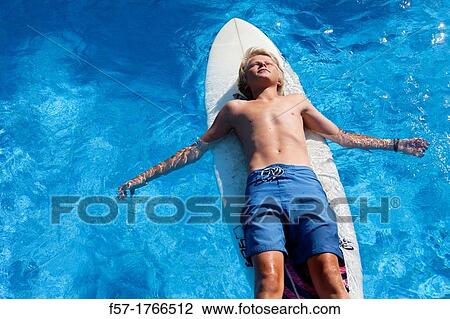 Stock Image - Teenage boy lying on his surfboard. Fotosearch