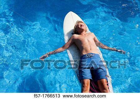 Stock Image - Teenage boy lying on his surfboard. Fotosearch