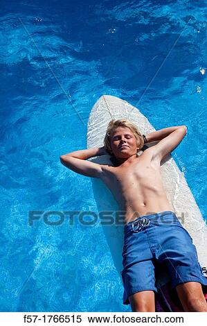 Teenage boy lying on his surfboard View Large Photo Image Stock Photography - Teenage boy lying on his surfboard. Fotosearch