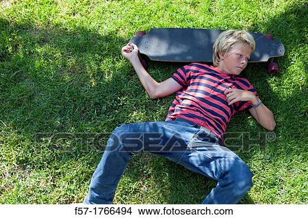 Teenage boy lying on the grass with his longboard View Large Photo Image Picture - Teenage boy lying on the grass with his longboard. Fotosearch