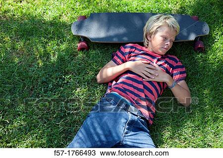 Teenage boy lying on the grass with his longboard View Large Photo Image Stock Image - Teenage boy lying on the grass with his longboard. Fotosearch