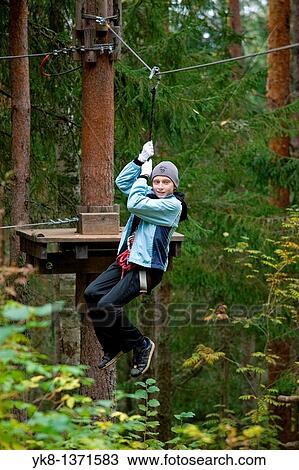 Stock Image - Teenage boy on zip wire in adventure park trail in Otep??, Estonia. Fotosearch