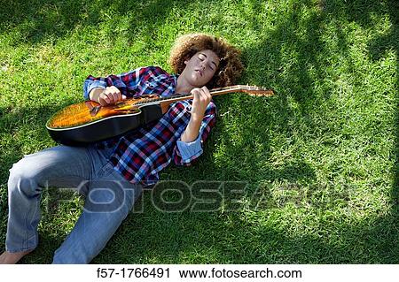 Teenage boy playing his guitar on the grass View Large Photo Image Stock Image - Teenage boy playing his guitar on the grass. Fotosearch