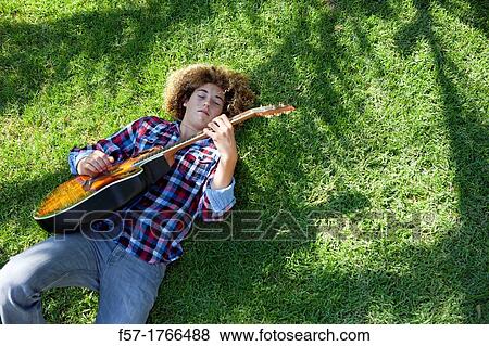 Teenage boy playing his guitar on the grass View Large Photo Image Stock Photo - Teenage boy playing his guitar on the grass. Fotosearch