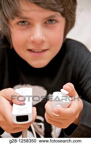 Stock Image - teenage boy playing with his nintendo console holding wiimote and nunchuck. Fotosearch