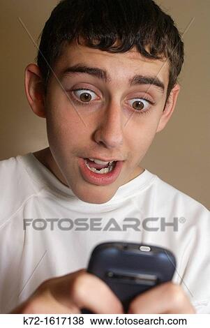 Teenage boy reads surprising text on cellphone View Large Photo Image Stock Photo - Teenage boy reads surprising text on cellphone. Fotosearch