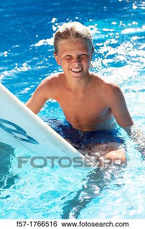 Teenage boy sitting on his surfboard View Large Photo Image Stock Photograph - Teenage boy sitting on his surfboard. Fotosearch