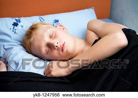 Stock Photograph - Teenage boy sleeping in bed. Fotosearch