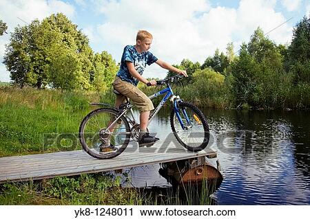 Teenage Boy Standing with Bicycle on Wooden Platform by Water View Large Photo Image Stock Image - Teenage Boy Standing with Bicycle on Wooden Platform by Water. Fotosearch