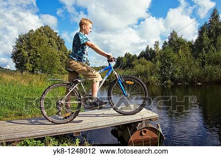 Teenage Boy Standing with Bicycle on Wooden Platform by Water View Large Photo Image Stock Image - Teenage Boy Standing with Bicycle on Wooden Platform by Water. Fotosearch