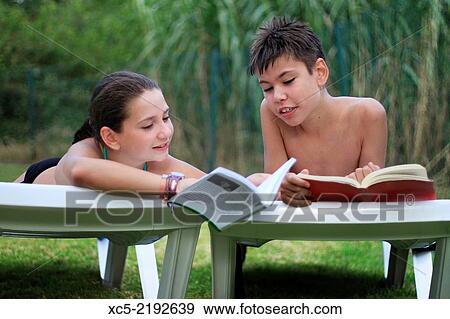 teenage brothers lying on a sun lounger and read a book outside in the garden. View Large Photo Image Stock Photo - teenage brothers lying on a sun lounger and read a book outside in the garden.. Fotosearch