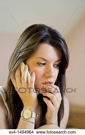 Picture - Teenage girl chatting with her mobile phone in bedroom. Fotosearch