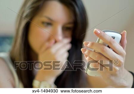 Stock Image - Teenage girl chatting with her mobile phone in bedroom. Fotosearch