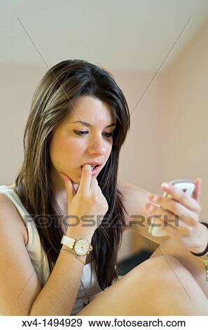 Stock Photo - Teenage girl chatting with her mobile phone in bedroom. Fotosearch