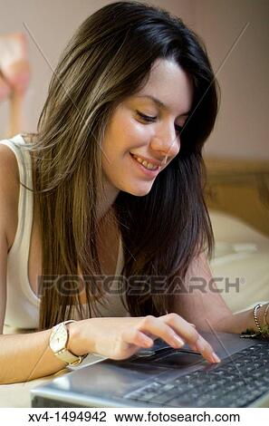 Stock Image - Teenage girl chatting with notebook in her home. Fotosearch