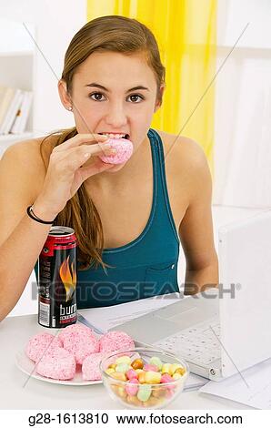 Teenage girl doing her homework and using her computer, while eating sweets, cookies, and drinking energy drinks View Large Photo Image Stock Image - Teenage girl doing her homework and using her computer, while eating sweets, cookies, and drinking energy drinks. Fotosearch