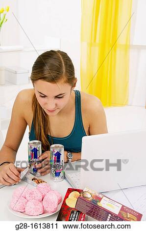 Teenage girl doing her homework and using her computer, while eating sweets, cookies, and drinking energy drinks View Large Photo Image Stock Image - Teenage girl doing her homework and using her computer, while eating sweets, cookies, and drinking energy drinks. Fotosearch