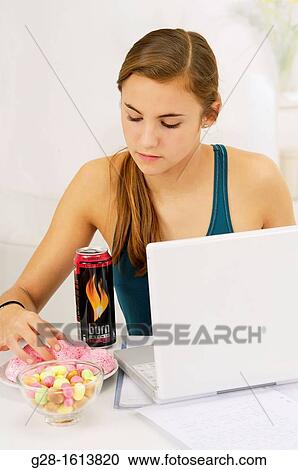Teenage girl doing her homework and using her computer, while eating sweets, cookies, and drinking energy drinks View Large Photo Image Stock Image - Teenage girl doing her homework and using her computer, while eating sweets, cookies, and drinking energy drinks. Fotosearch