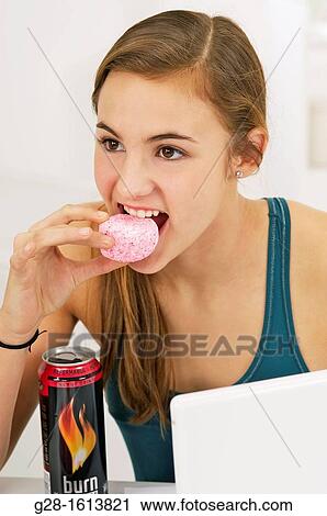 Teenage girl doing her homework and using her computer, while eating sweets, cookies, and drinking energy drinks View Large Photo Image Stock Image - Teenage girl doing her homework and using her computer, while eating sweets, cookies, and drinking energy drinks. Fotosearch