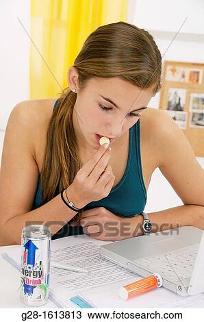 Teenage girl, doing her homework on her computer and eating a tablet of vitamin C, and drinking an energy drink View Large Photo Image Stock Image - Teenage girl, doing her homework on her computer and eating a tablet of vitamin C, and drinking an energy drink. Fotosearch