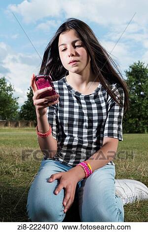 Stock Image - Teenage girl looking at her phone.. Fotosearch