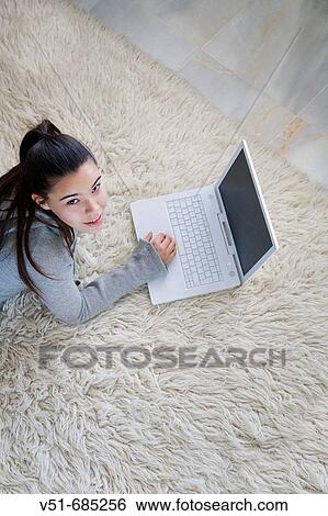 Teenage girl lying on the carpet using laptop View Large Photo Image Stock Photograph - Teenage girl lying on the carpet using laptop. Fotosearch