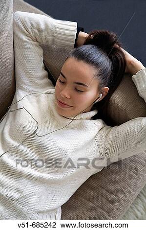 Teenage girl lying on the couch listening to music View Large Photo Image Stock Image - Teenage girl lying on the couch listening to music. Fotosearch