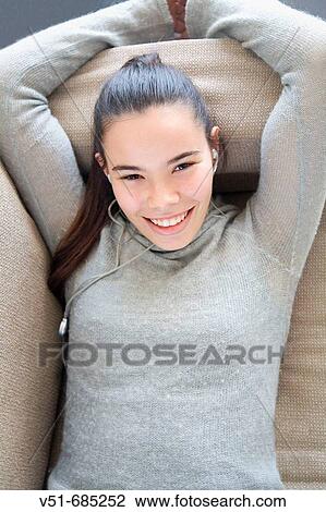 Teenage girl lying on the couch listening to music and smiling View Large Photo Image Stock Image - Teenage girl lying on the couch listening to music and smiling. Fotosearch