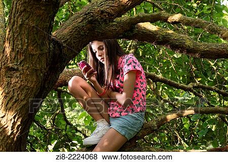 Stock Photo - Teenage girl on her mobile phone in the park.. Fotosearch