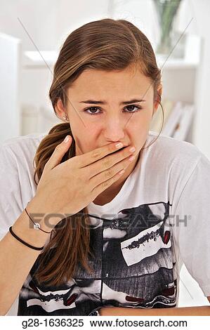 Stock Photography - Teenage girl putting her hand in front of her mouth: afraid, forgot something, belching, stomach problems, etc..... Fotosearch