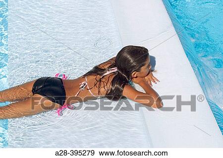 Teenage girl relaxing at edge of a swimming pool. View Large Photo Image Stock Photo - Teenage girl relaxing at edge of a swimming pool.. Fotosearch