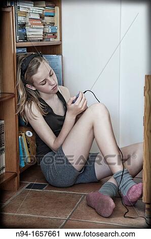 Teenage girl sitting on the floor of his room, consultation messages from your mobile phone. View Large Photo Image Stock Image - Teenage girl sitting on the floor of his room, consultation messages from your mobile phone.. Fotosearch